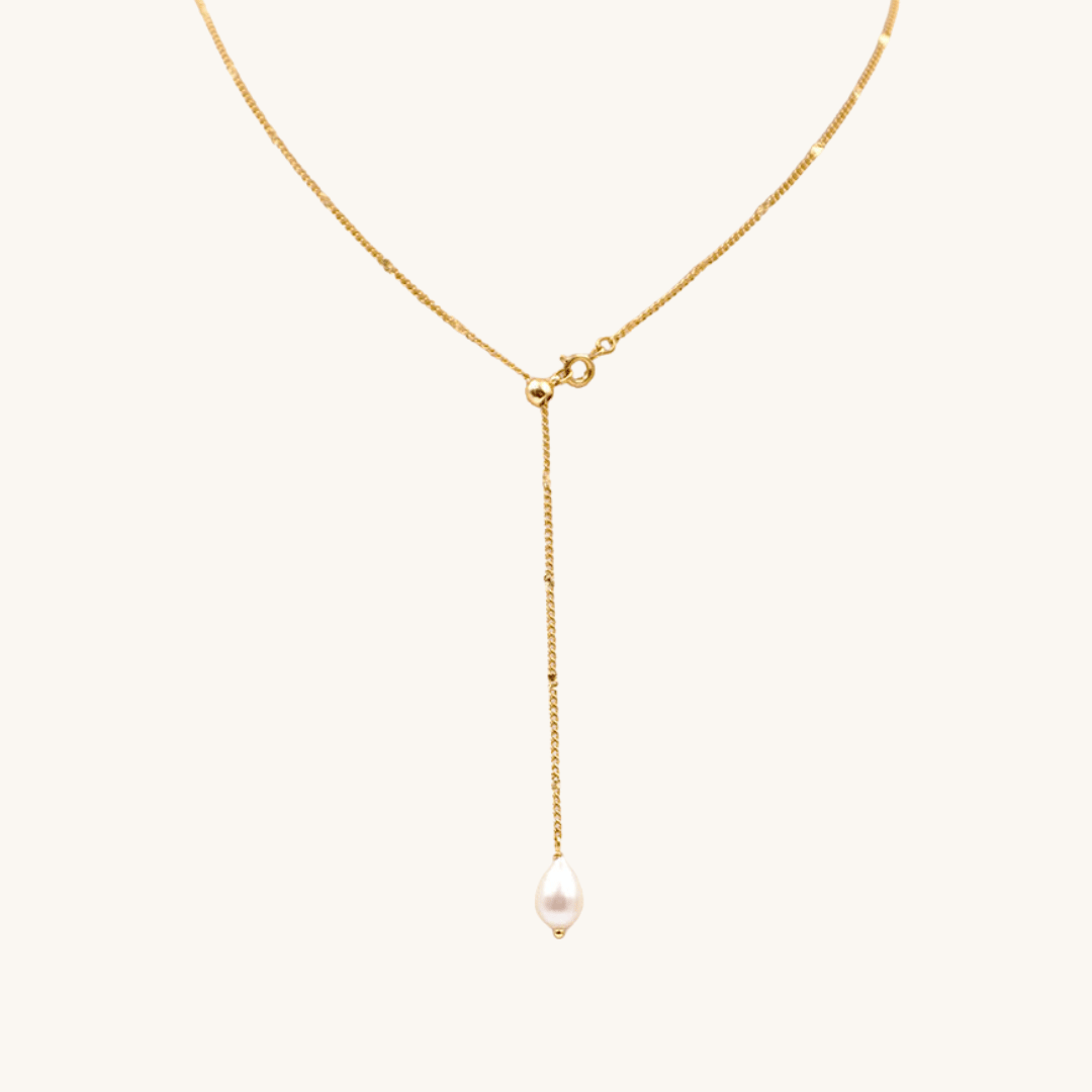Collana a Y oro 18k waterproof con pendente perla a goccia su sfondo crema Unique et Spécial
