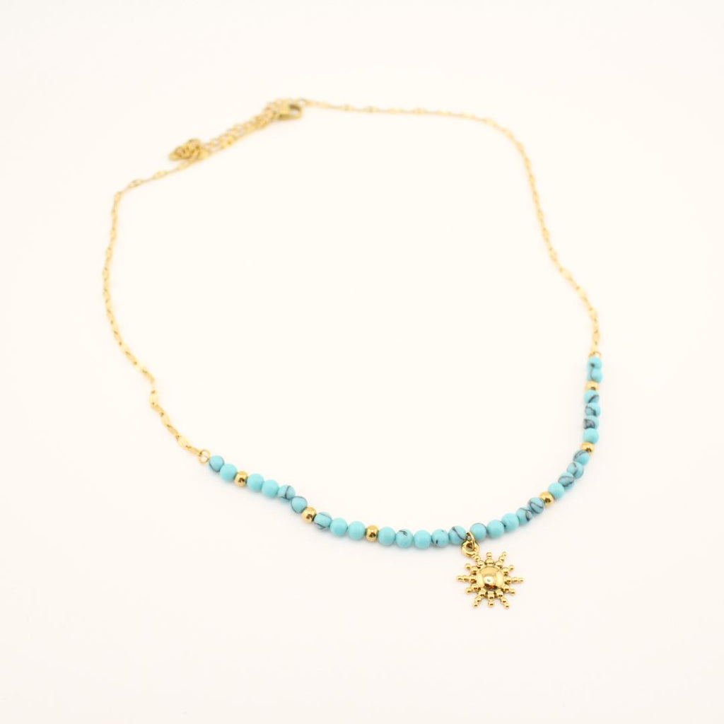 Collana dorata con perline turchesi e ciondolo sole in primo piano