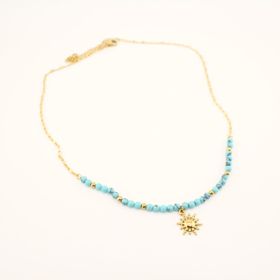 Collana dorata con perline turchesi e ciondolo sole in primo piano