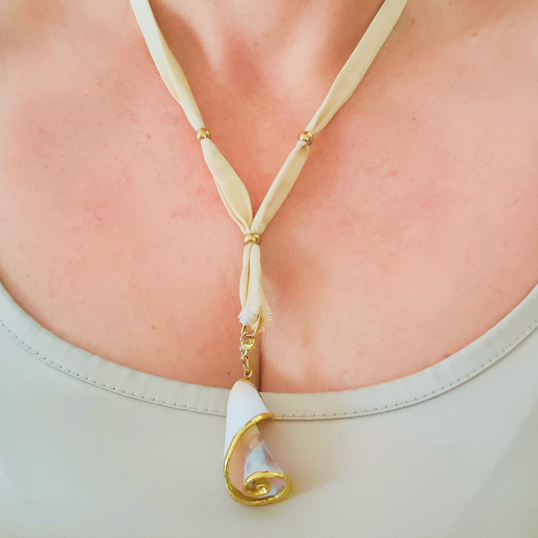 Collana indossata: nastro di seta avorio e ciondolo conchiglia dorata con gemma viola