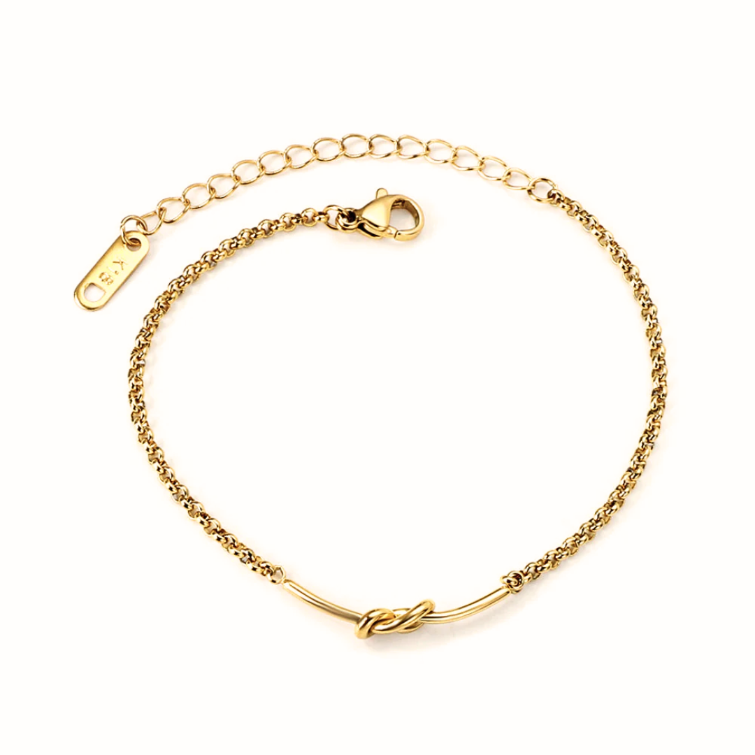 Bracciale con catena morbida e elemento centrale a forma di nodo dorato.