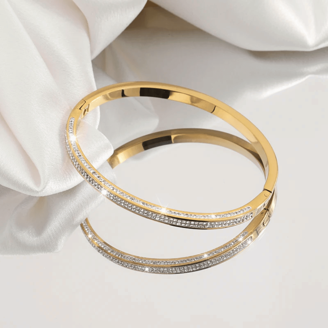 Bracciali rigidi in oro con pavé di zirconi, sovrapposti su supporto.