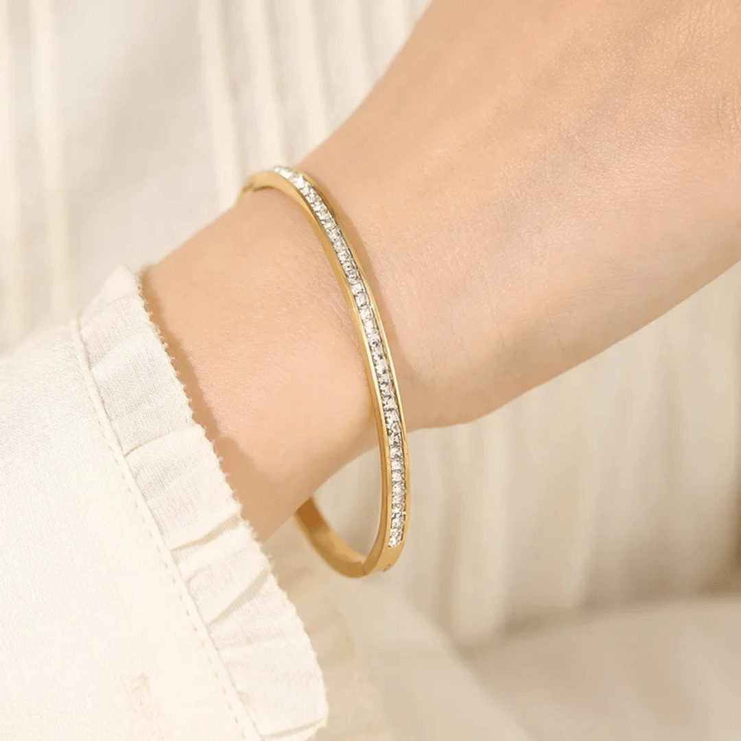 Bracciale rigido in oro con pavé di zirconi, indossato al polso.