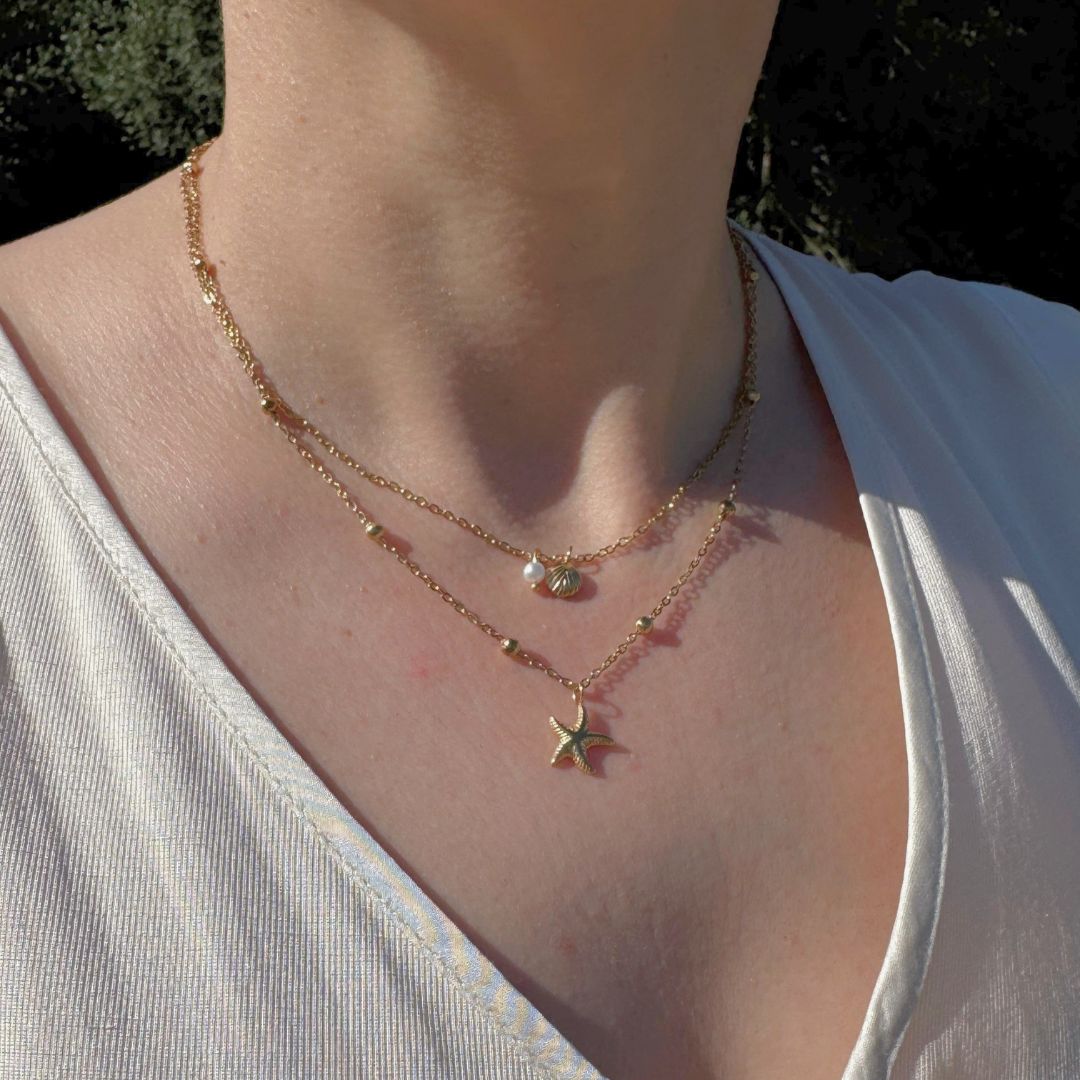 Collana multi-strato dorata con stella marina e conchiglia su collo