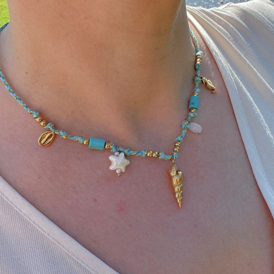 Collana in perline turchesi con ciondoli dorati, stellina bianca e conchiglia.