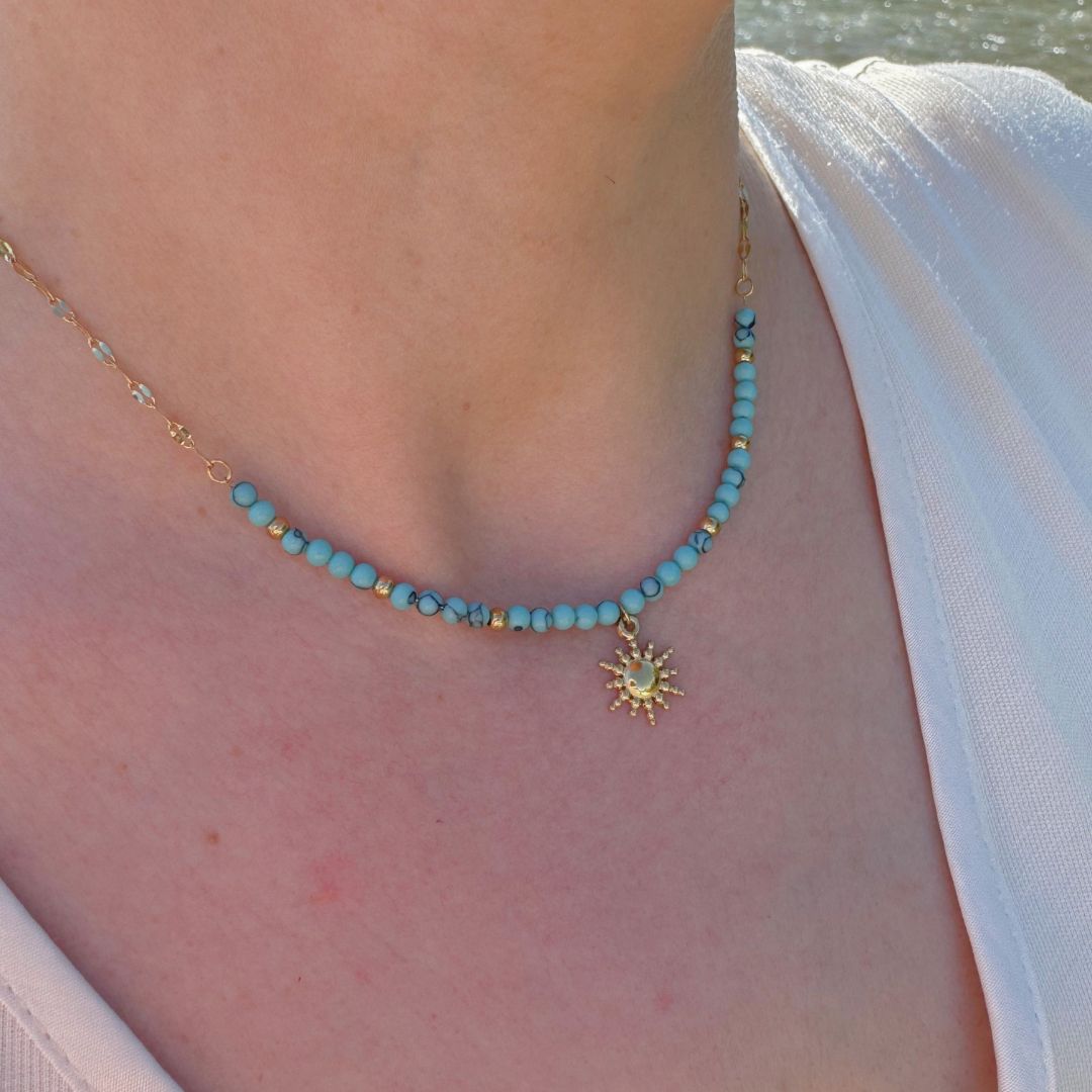 Collana con perline turchesi e ciondolo sole dorato, dettaglio al collo