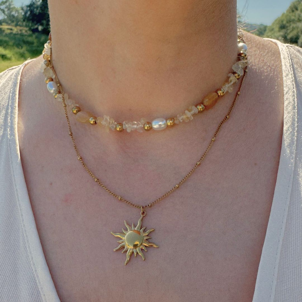 Collana doppia in oro 18K con perline multicolor e pendente sole sul collo
