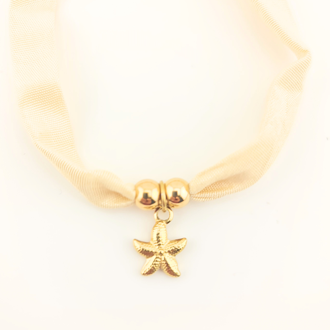 Bracciale in seta avorio con perle dorate e ciondolo a stella marina.