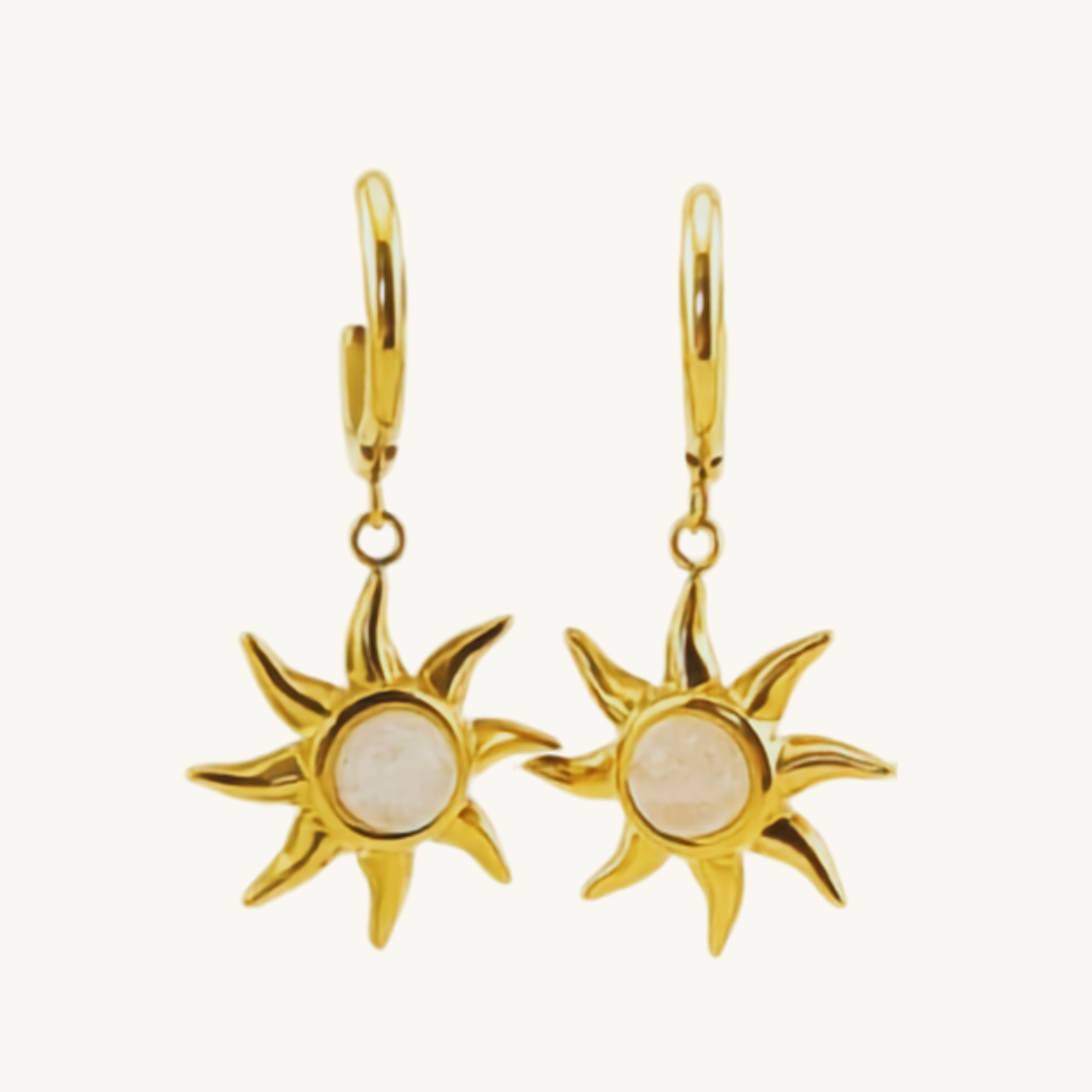 Illumina il tuo stile con gli orecchini a cerchio Hélios. Pendente a forma di sole dorato con perla centrale, in acciaio inox 316L waterproof e anallergico.