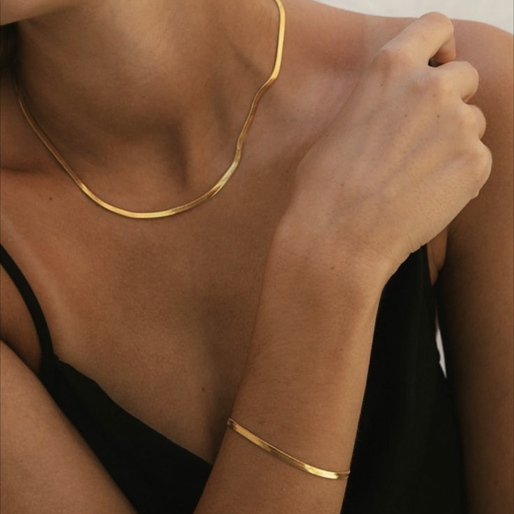 Collana oro 18 carati indossata al collo, con bracciale sottile al polso