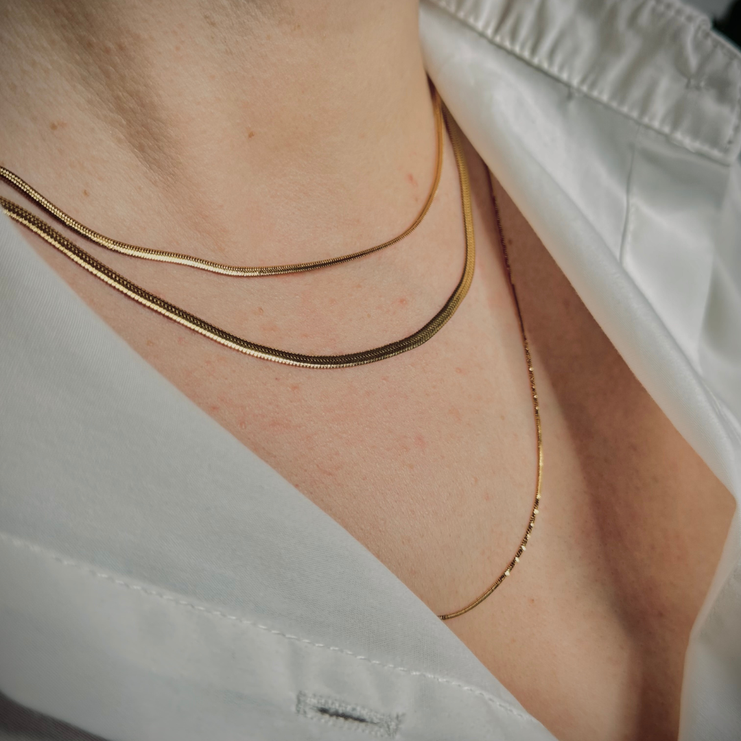 Primo piano di donna che indossa layering di collane sottili snake